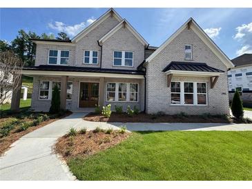 Beautiful two-story brick home with well-manicured lawn, covered front porch, and professionally landscaped yard at 2455 Bleckley Pl, Cumming, GA 30041
