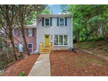 Charming home with light grey brick, blue shutters, a bright yellow door and mature trees at 2780 Northwood Court Sw Ct, Marietta, GA 30060