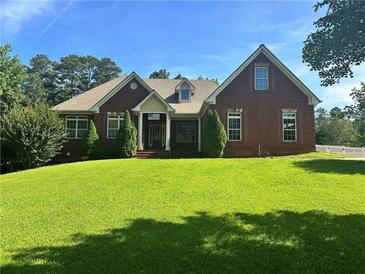 Charming single-story red brick home featuring a well-manicured lawn, lush landscaping, and a welcoming front entrance at 20 Wood Lawn Springs Trl, Covington, GA 30014