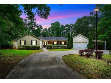 Charming single-story home with lush landscaping, a curved driveway, and a two-car garage and car port at 280 W Knight W Rd, Mcdonough, GA 30252
