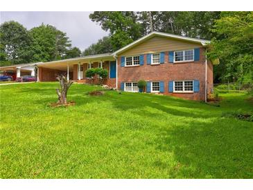 Charming brick home featuring a lush green lawn, covered parking, and inviting curb appeal at 5739 Cobb Mdw, Norcross, GA 30093