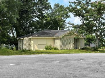Quaint one-story home with a gable roof, lattice facade, and surrounded by mature trees on an overgrown lot at 1891 Bennett Rd, Grayson, GA 30017
