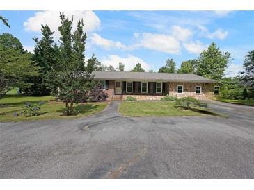 Charming one-story home featuring stone accents, mature landscaping, and an expansive front yard at 6880 Mark Turner Rd, Lithia Springs, GA 30122