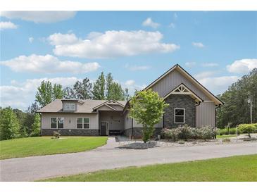 Charming single-story home with gray siding, stone accents, manicured lawn, and well-maintained landscaping at 411 Johnson Rd, Locust Grove, GA 30248