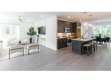 Bright and airy living room with hardwood floors flowing into the kitchen with a granite island and modern appliances at 371 Grant Cir # 1813, Atlanta, GA 30315