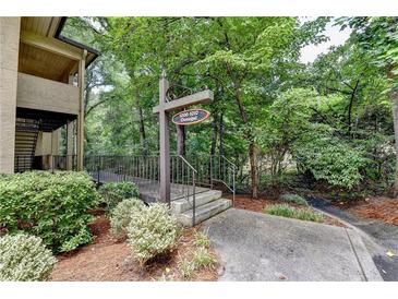 Community entrance sign with lush greenery and mature trees around walkway and building at 1010 Donegal Se, Smyrna, GA 30080