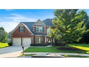 Charming two-story brick home featuring lush landscaping, a two-car garage, and a welcoming front porch at 1496 Clarecastle Ln, Buford, GA 30519