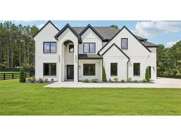 Stunning two-story home featuring a painted brick exterior, dark trim, arched entryway, and manicured lawn at 3205 Bold Springs Rd, Dacula, GA 30019