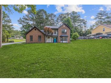 Charming brick two-story home boasts a manicured lawn and a bright blue front door at 4000 Brittan Glade Trl, Snellville, GA 30039