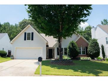 Charming home with manicured lawn, mature tree, and a well-maintained flower bed in the front yard at 3050 Baymount Dr, Lawrenceville, GA 30043