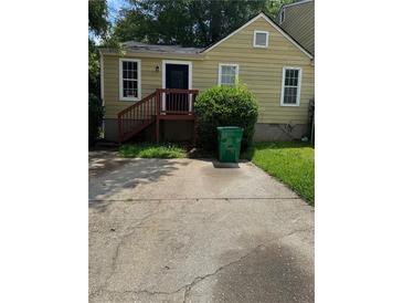 Cozy yellow home featuring a quaint entrance deck and a concrete driveway leading up to the stairs at 3490 Kingswood Trl, Decatur, GA 30034