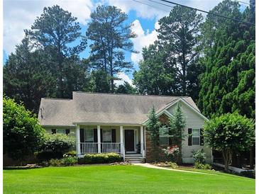 Charming home featuring a quaint front porch and beautifully manicured lawn, nestled among mature trees at 60 Stonehedge Dr, Buford, GA 30518