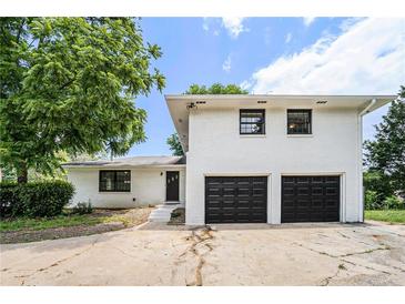 Two-story home features white painted brick, black windows, two car garage, and mature landscaping at 1894 Twin Falls Rd, Decatur, GA 30032
