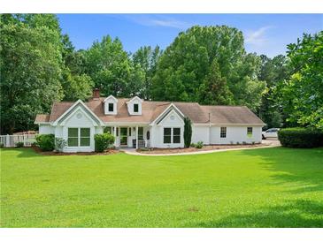 Charming white home boasts a lush green lawn, mature trees, and inviting curb appeal at 145 Deep Step Rd, Covington, GA 30014