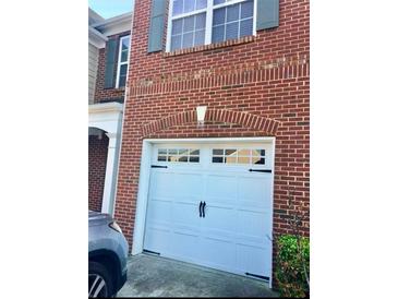 Attached garage with arched entry and carriage style door matches the red brick home's exterior at 1870 Garbrooke, Lawrenceville, GA 30046