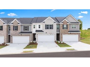New construction townhomes displaying mixed brick and siding, along with two-car garages and modern architectural details at 225 Silver Moon Dr, Loganville, GA 30052