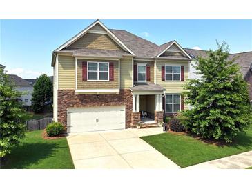 Charming two-story home with stone accents, a well-manicured lawn, and a two-car garage at 253 Orchard Trl, Holly Springs, GA 30115