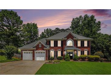 Charming two-story brick home with a well-manicured lawn, lush landscaping, and a two-car garage at 3055 Dogwood Hollow Ln, Lawrenceville, GA 30043
