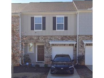Two-story townhome with brick and siding, a one-car garage, and a manicured front yard at 136 Swindon Dr, Mcdonough, GA 30253