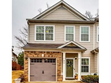 Charming townhouse showcasing a brick-accented garage and inviting front door with a decorative wreath at 7750 Carnegie Dr, Fairburn, GA 30213