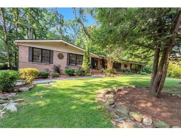 Charming brick home featuring a lush lawn, mature trees, and inviting curb appeal at 2994 Baker Ridge Nw Dr, Atlanta, GA 30318