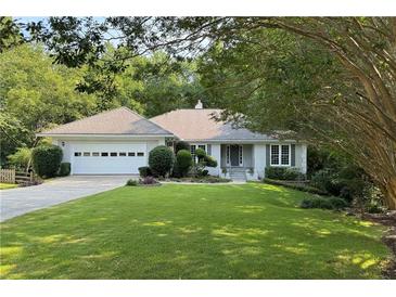 Charming one-story home with a well-manicured lawn, mature trees, and attached two car garage at 1956 Regents Way, Marietta, GA 30062