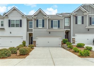 Charming townhome featuring a two-car garage, gray siding, and lovely landscaping at 738 Woodstock Grove Dr, Woodstock, GA 30188