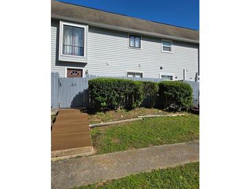 Charming townhome with manicured front yard and gray siding, complemented by a quaint wooden fence at 22 Fairview Dr, Jonesboro, GA 30238