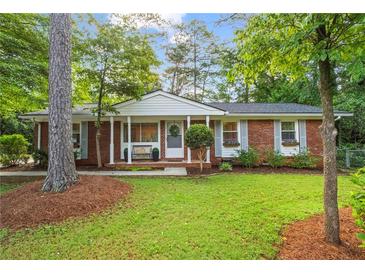 Charming brick home with a well-maintained front yard, mature trees, and inviting front porch at 2703 Carolyn Se Dr, Smyrna, GA 30080