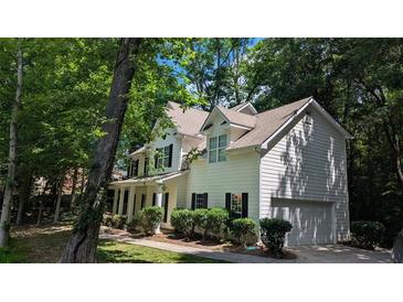 Traditional two-story home features a white exterior, black shutters and attached garage nestled among mature trees at 3618 Prescot Way, Douglasville, GA 30135