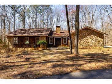 Charming ranch-style house with stone and wood exterior, set amidst mature trees, offers a peaceful retreat at 166 Muse Rd, Fayetteville, GA 30214