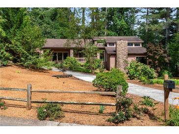 Charming home featuring a stone chimney, lush landscaping, and a welcoming driveway at 3152 Sycamore Ln, Marietta, GA 30066