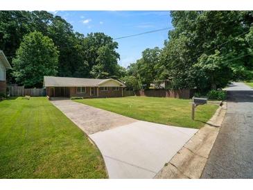 Traditional brick ranch-style home with a well-maintained lawn, mature trees, and a spacious driveway at 3464 Navaho Se Trl, Smyrna, GA 30080