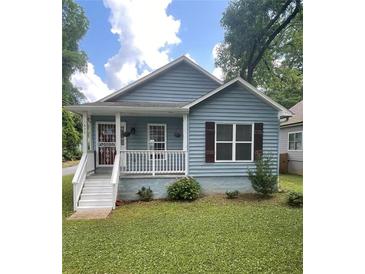 Charming blue house featuring a cozy front porch and well-maintained lawn at 1833 Phillips Ave, East Point, GA 30344
