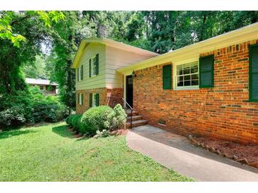 Charming brick home featuring green shutters, established landscaping and a manicured lawn at 2802 Leisure Woods Ln, Decatur, GA 30034