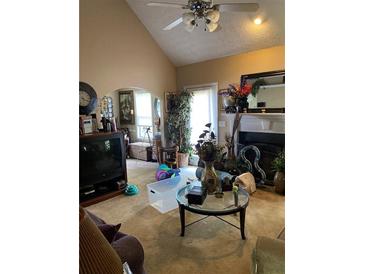 Cozy living room featuring a ceiling fan, a fireplace, and various decorative items at 413 W Wind Dr, Villa Rica, GA 30180