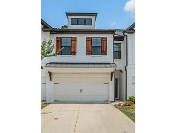 Charming townhome featuring a two-car garage, warm wood shutters, and a beautifully painted white brick facade at 211 N Auburn Landing Pl, Auburn, GA 30011