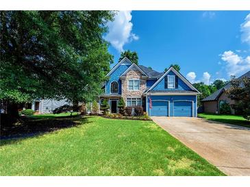 Inviting blue two-story home with stone accents, a well-manicured lawn, and an attached two-car garage at 29 Sedgefield Overlook, Dallas, GA 30157