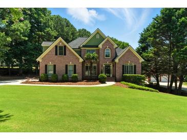 Charming two-story brick home with a well-manicured lawn and lush landscaping at 2832 Windrush Dr, Buford, GA 30518