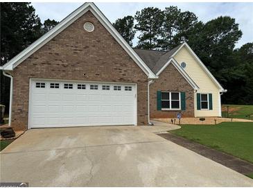 Charming brick and siding home featuring an attached garage and well-maintained front lawn at 521 Deadwood Trl, Locust Grove, GA 30248