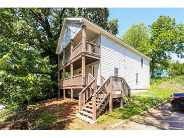 Two-story home with double balconies, wooden steps, and charming curb appeal surrounded by lush trees at 1112 Smith St, Atlanta, GA 30310