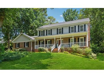 Charming two-story brick home featuring a welcoming front porch and well-manicured lawn surrounded by mature trees at 3835 Thornhill Sw Dr, Lilburn, GA 30047