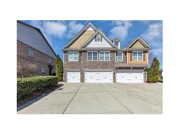 Three-story townhome with brick facade and attached three-car garage, manicured landscaping at 805 Pleasant Hill Nw Rd # 343, Lilburn, GA 30047