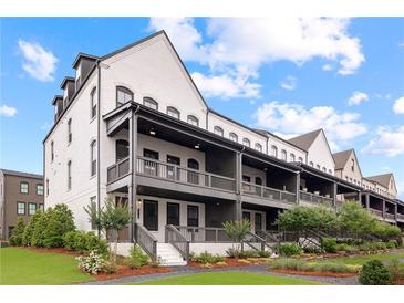 View of townhomes with covered front porches and landscaped lawns against a blue sky with clouds at 6710 Pippin Walk, Alpharetta, GA 30005