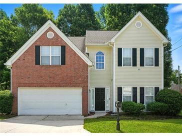 Charming two-story home with brick and siding exterior, an attached garage, and manicured landscaping at 5487 Walnut Lane Ln, Stonecrest, GA 30038