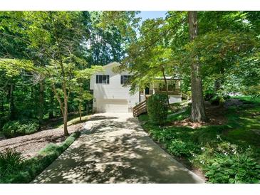 Charming home featuring a two-car garage and a well-manicured lawn, surrounded by lush trees and greenery at 86 Kelly Ct, Dallas, GA 30157
