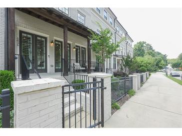 Charming townhouse exterior featuring painted brick, covered front porch, and stylish iron fence at 5836 Sandy Springs Cir, Atlanta, GA 30328