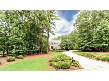 View of exterior with mature trees, landscaped yard and circular driveway leading to a brick home at 35 Inverleigh Row, Covington, GA 30014