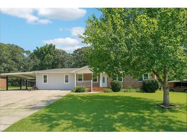 Charming single-story home with a well-maintained lawn, a covered carport, and mature trees at 6160 King Arthur Dr, Douglasville, GA 30135
