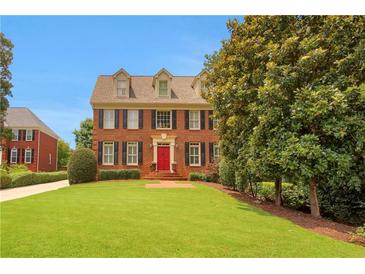 Charming two-story brick home with a well-manicured lawn, red door, and classic design at 4045 Boles Creek Dr, Duluth, GA 30096